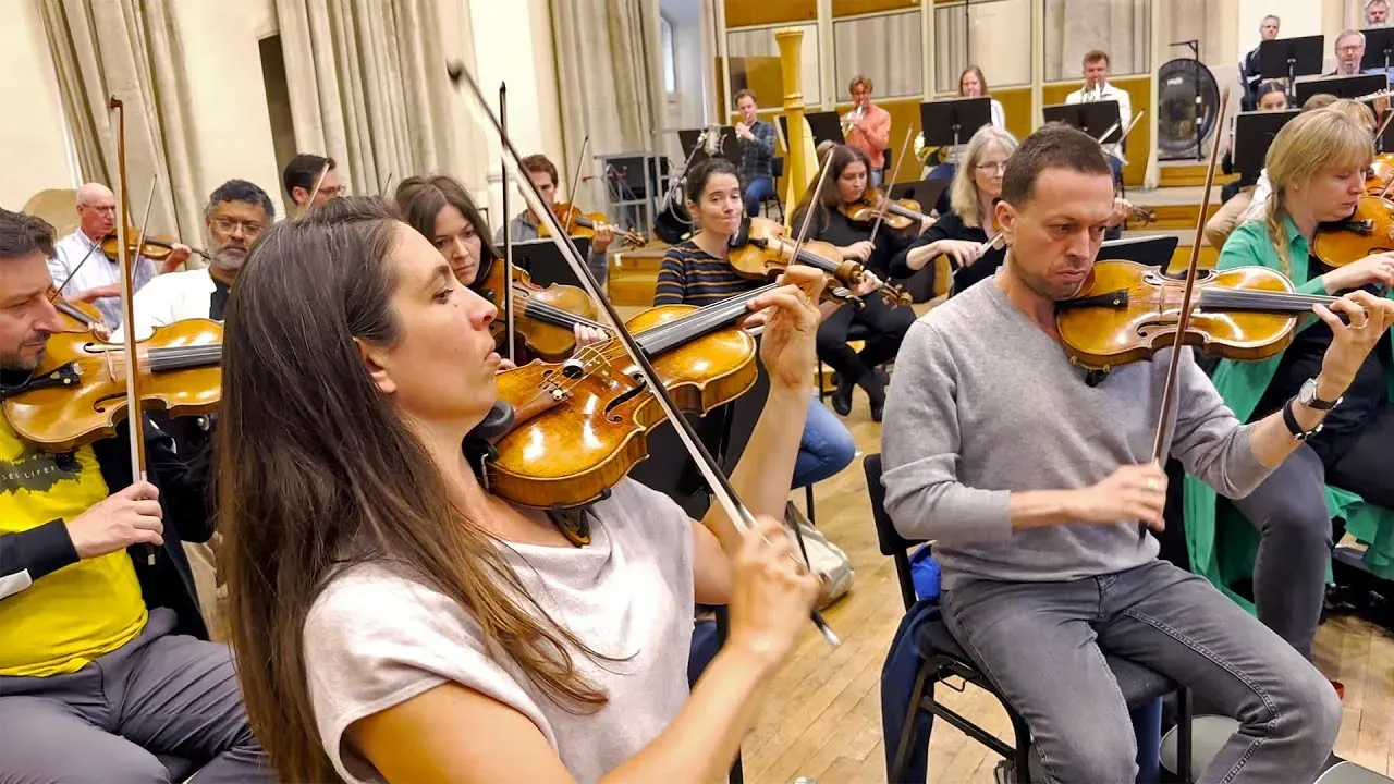 Violinists playing in a recording session, in shirtsleeves rather than concert dress.