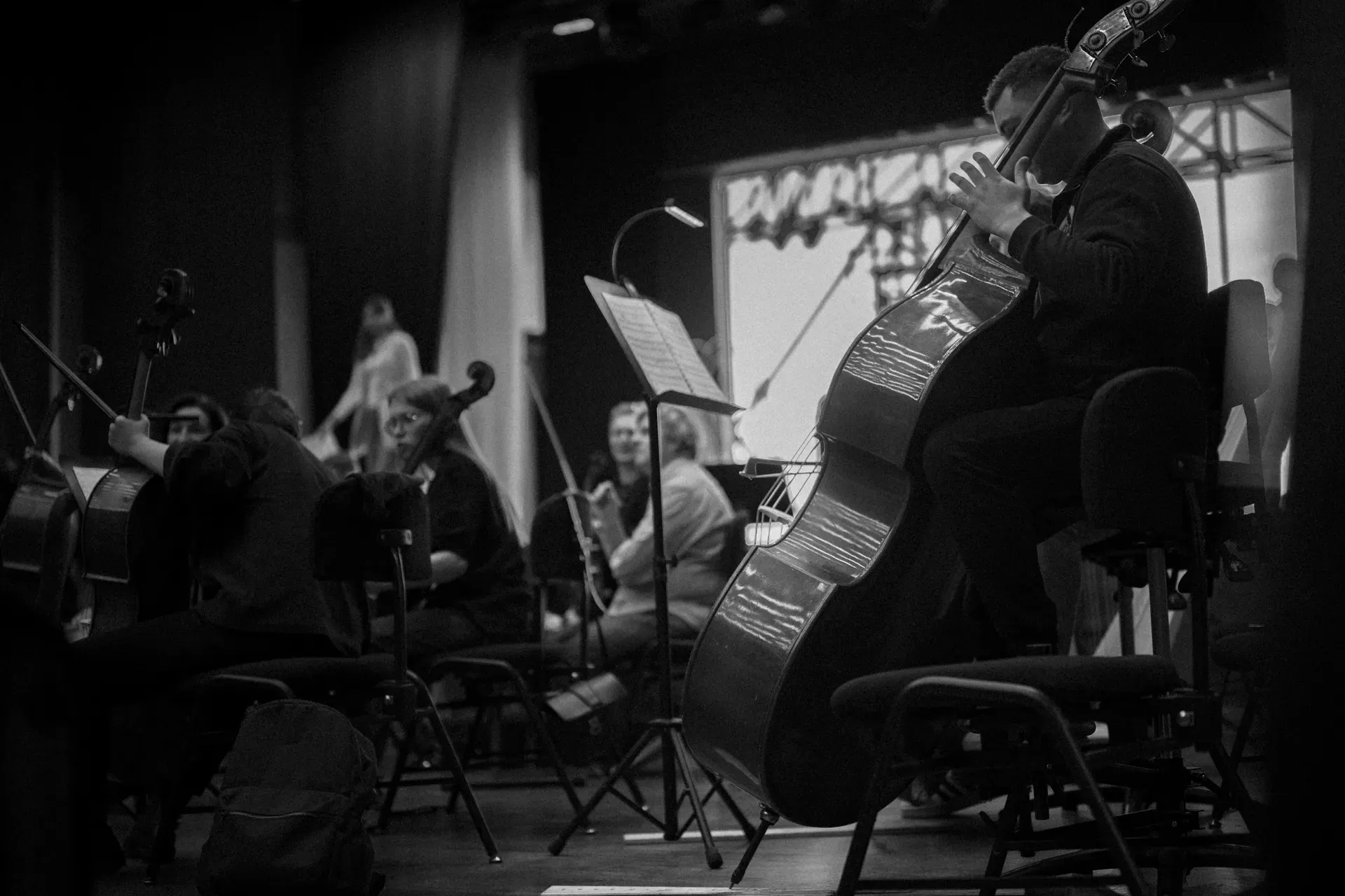 A rehearsal in black and white, a double bass and its player in the foreground.